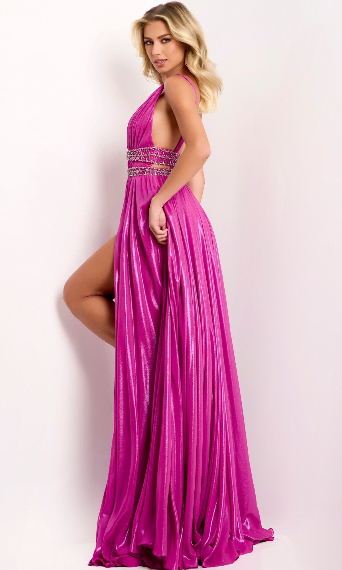 A woman wears the Jovani 42817 long prom dress in magenta, featuring a floor-length sleeveless design with a beaded waistband and high slit, standing against a plain light background.